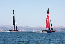 Color photograph of a racing catamaran underway with the starboard hull out of the water
